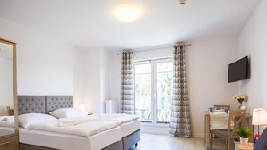 A modern hotel room with a large bed, a desk, a chair, and a TV. - VacationClub - Aquamarina Apartments (Swinoujscie)