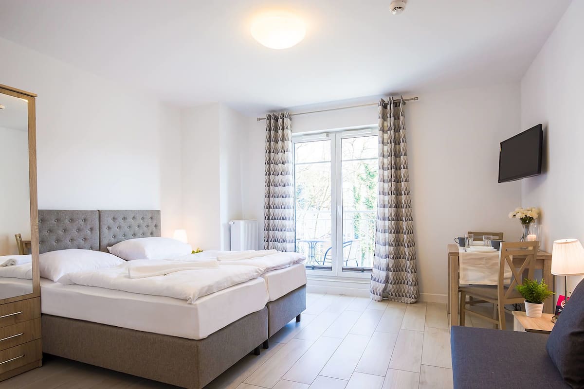 A modern hotel room with a large bed, a desk, a chair, and a TV.