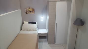 Ein Schlafzimmer mit Bett, Nachttisch, Kleiderschrank und einem an der Wand befestigten Regal mit Blumen und einem Fahrrad.