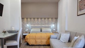Een moderne slaapkamer met een bed, een bank, een bureau en een stoel.