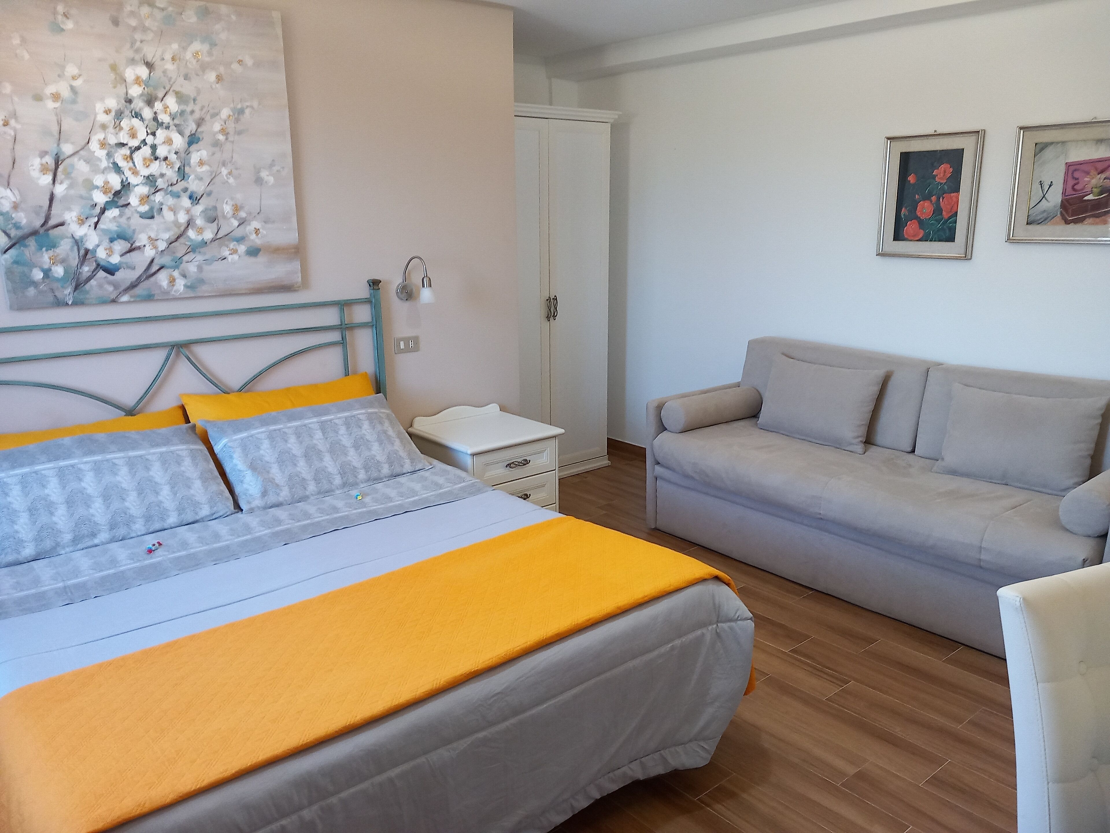 A bedroom with a bed, bedside table, nightstand, and a sofa.
