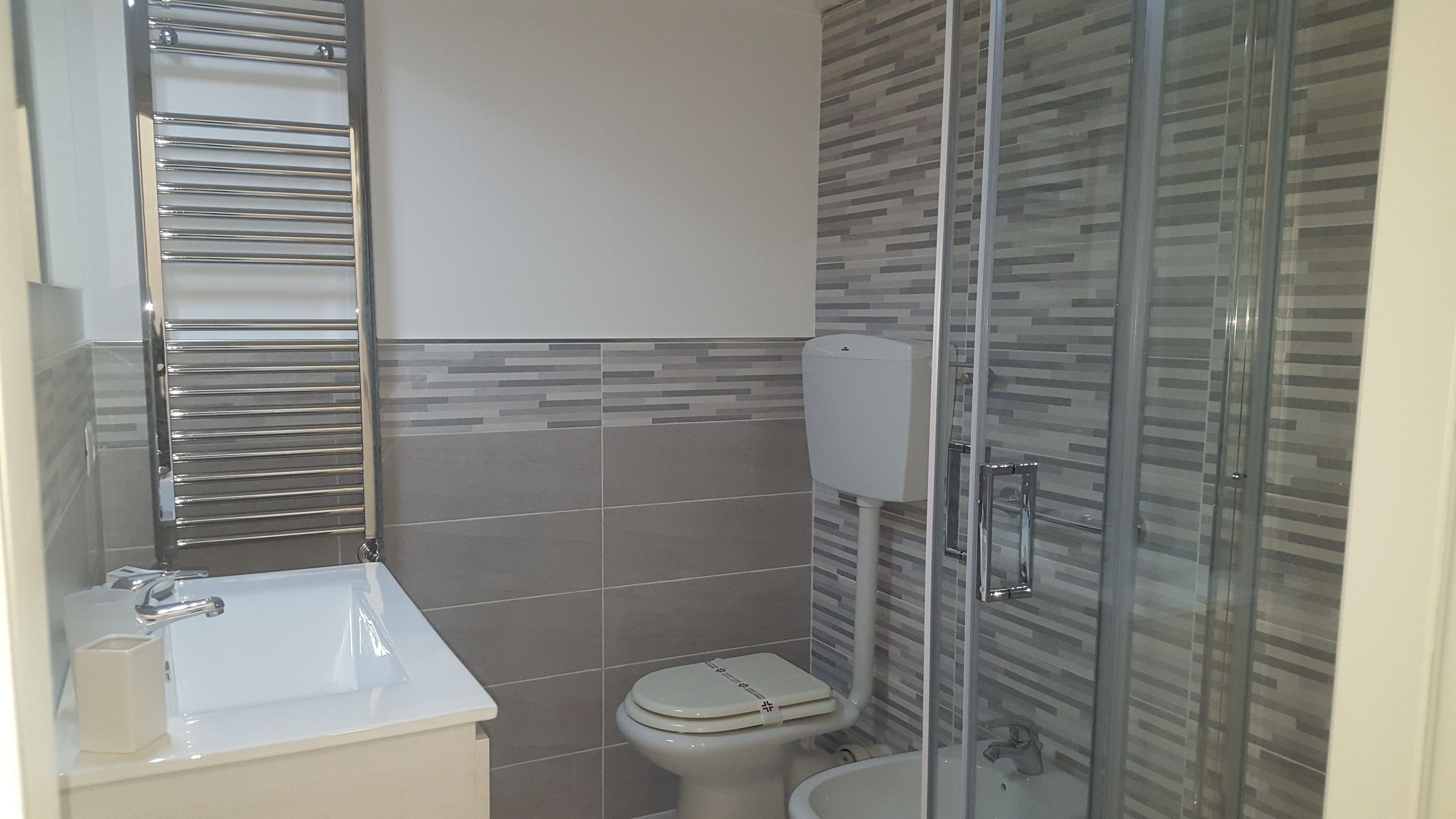A bathroom with a toilet, sink, and glass shower enclosure.