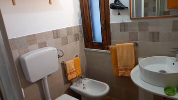 Une salle de bain équipée de toilettes, d’un bidet et d’un lavabo.