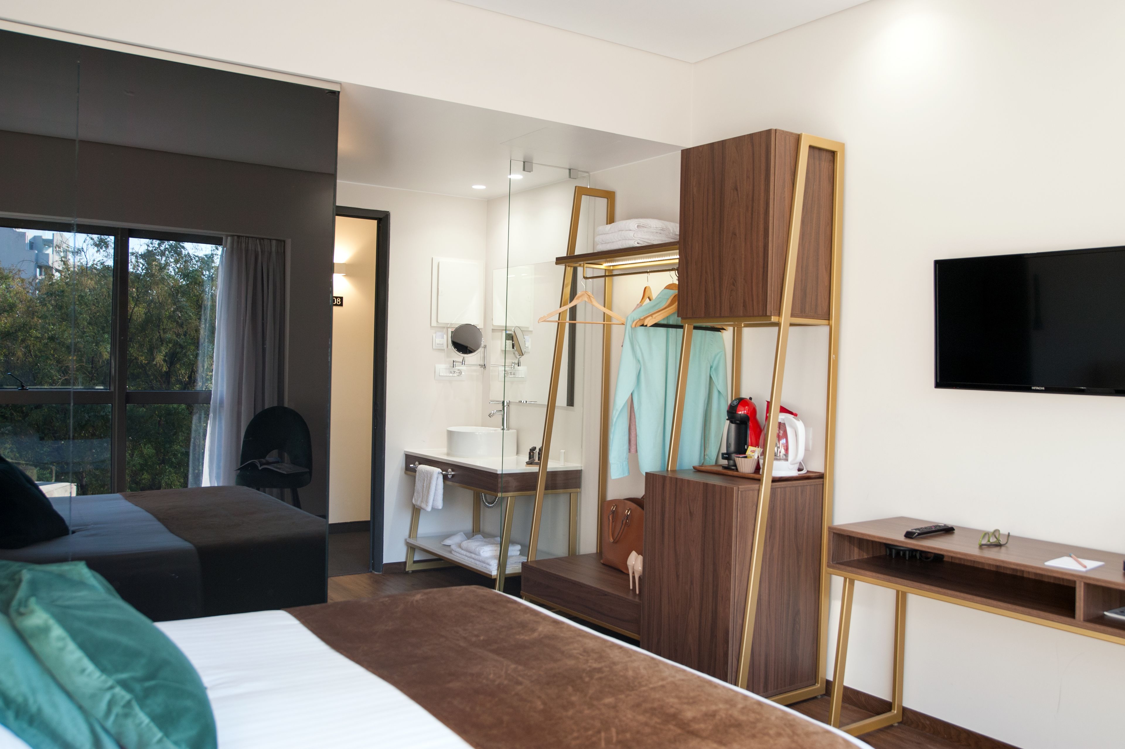 A modern hotel room with a bed, a desk, a wardrobe, and a TV.