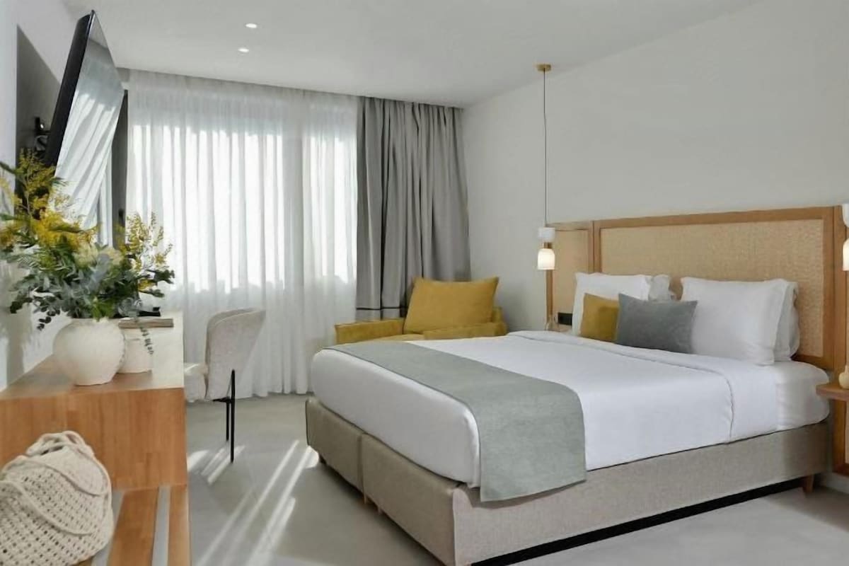Habitació d'hotel amb un llit gran, taules de nit, escriptori i una cadira.