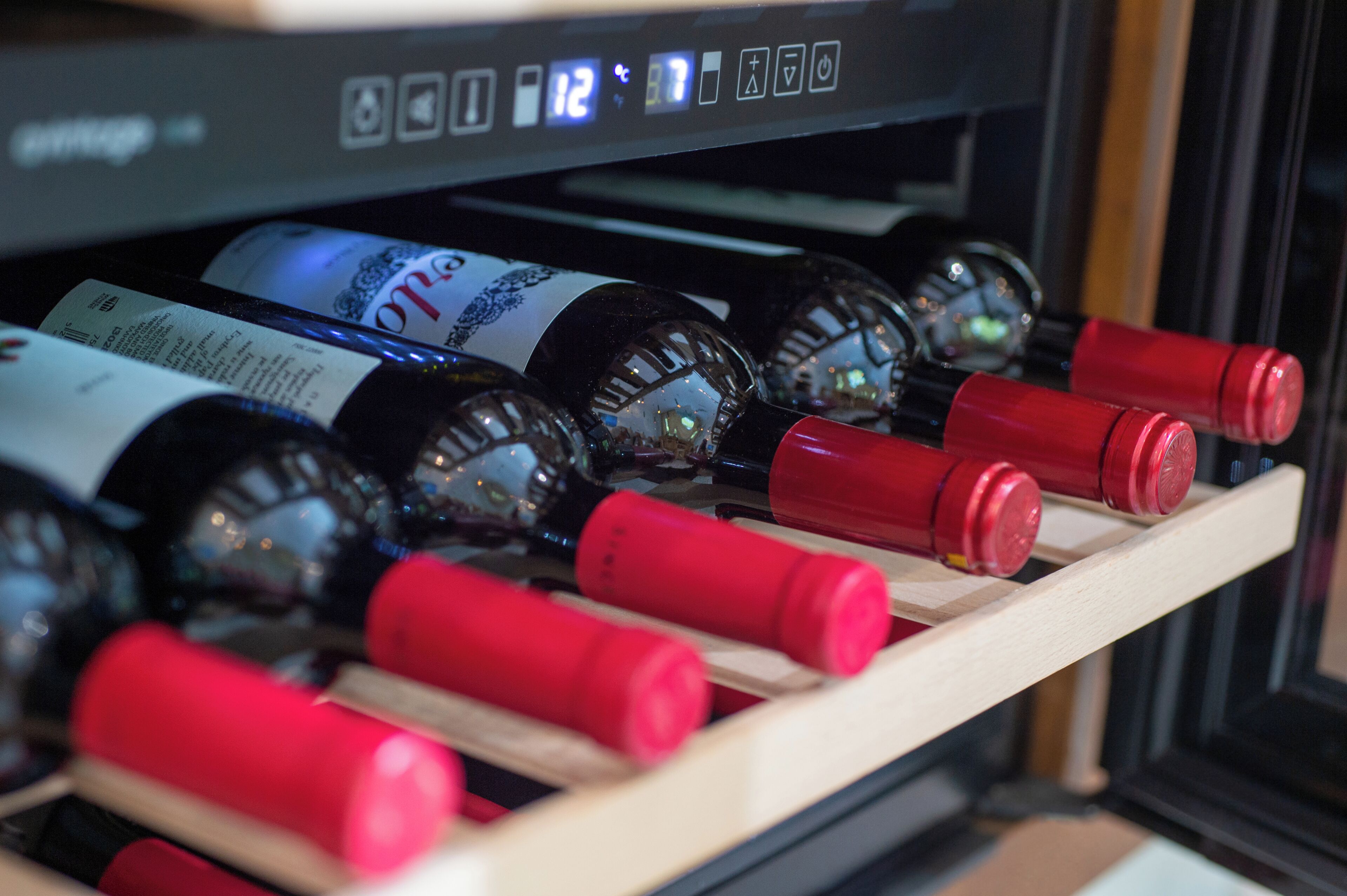 A wine rack with bottles and a digital clock.
