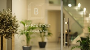 Una porta de vidre amb un logotip i text que indica que és l'entrada a l'hotel B for BOUTIQUE Athens Signature.