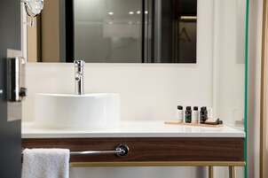 A bathroom with a white sink, a mirror, and a wooden vanity.