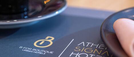 A close-up of a hotel brochure with the text 'ATHENA SIGNAL HOTEL' and 'B FOR BOUTIQUE URBAN HOTELS'.