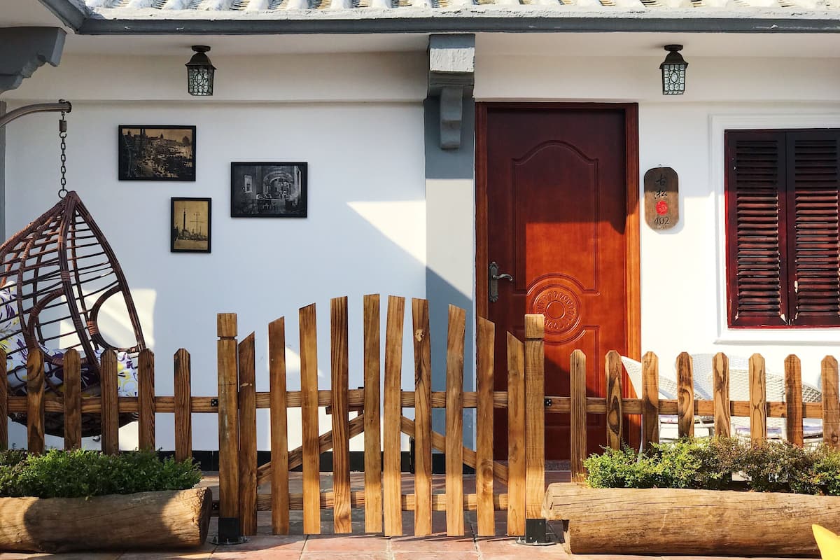 Un edificio tradicional con una verja de madera, una puerta roja y un tejado de tejas.