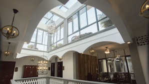 Un interior espacioso con techo alto, ventanas grandes y una imponente escalera.