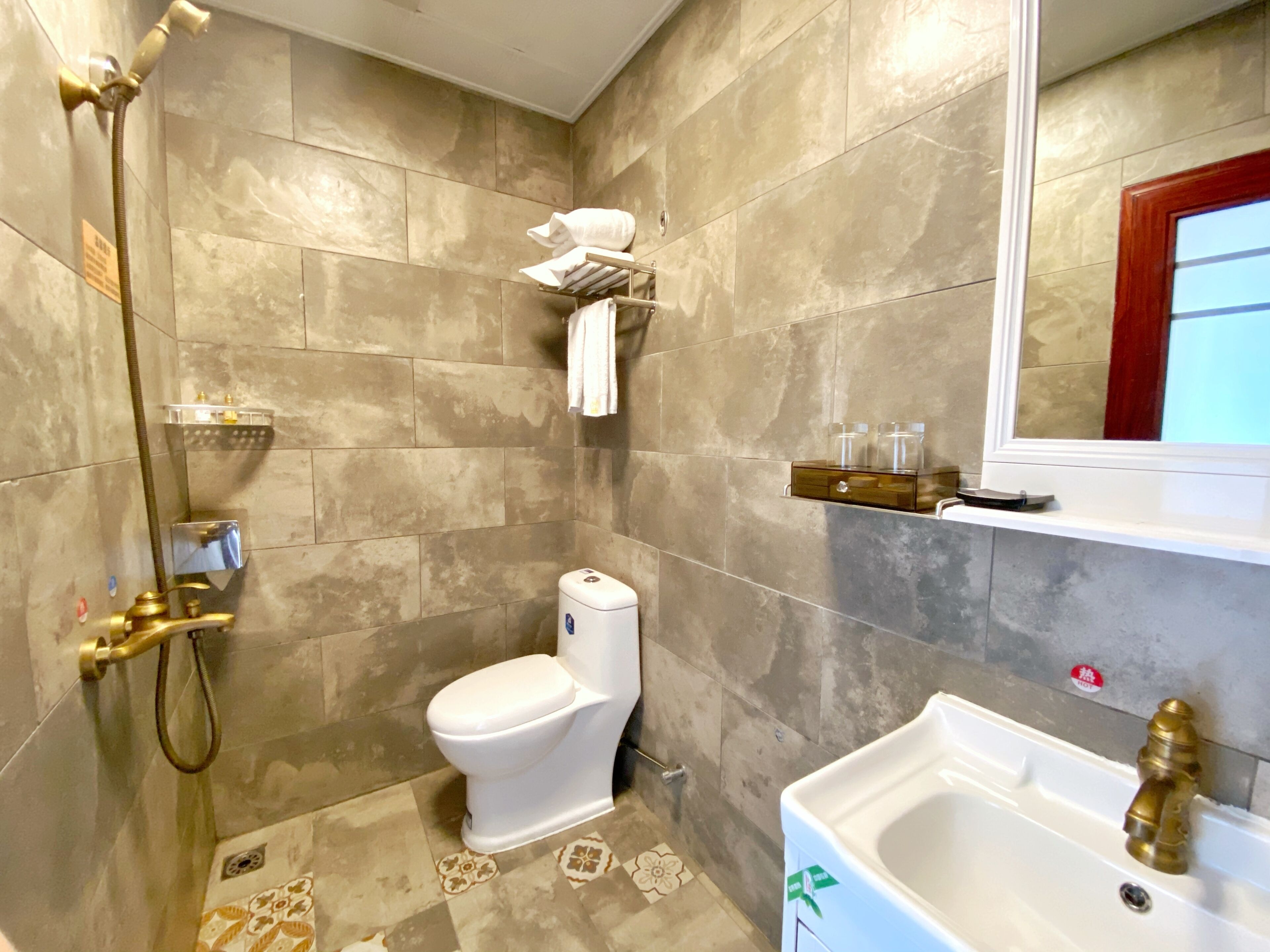 A bathroom with a shower, toilet, sink, and a mirror.