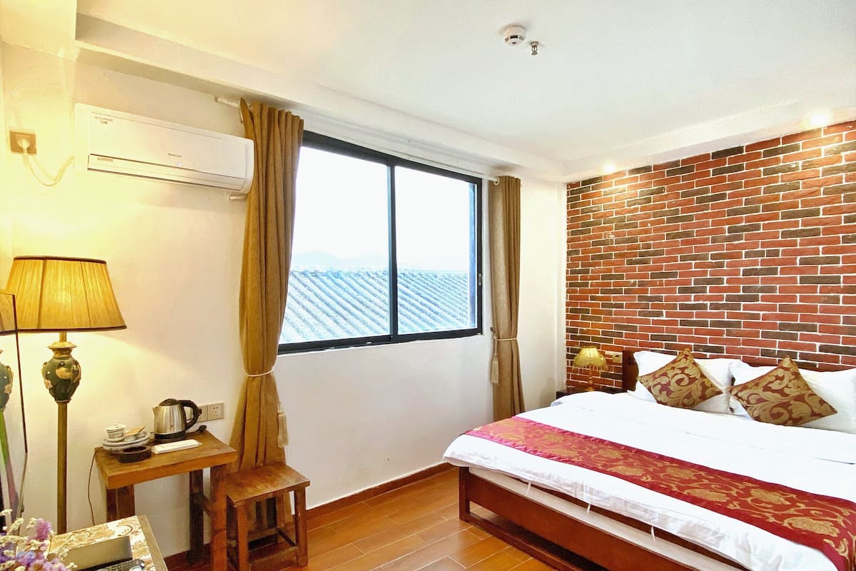 Una habitación de hotel con una cama, un escritorio, una lámpara y vistas al exterior.