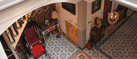 Un interior con una silla roja, un escritorio, una lámpara y una guitarra.