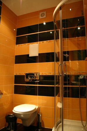 A bathroom with a glass-enclosed shower, a toilet, and a towel rack.