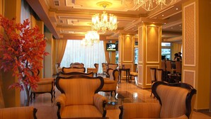 A hotel lobby with plush seating, a large chandelier, and a television in the background. - Kiten Beach (Kiten)