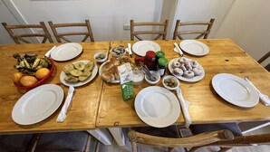 A wooden dining table set with plates, bowls, and various food items. - Masaya Suites (Hurghada)