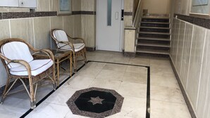 A hallway with two wicker chairs, a door, and a staircase. - Masaya Suites (Hurghada)