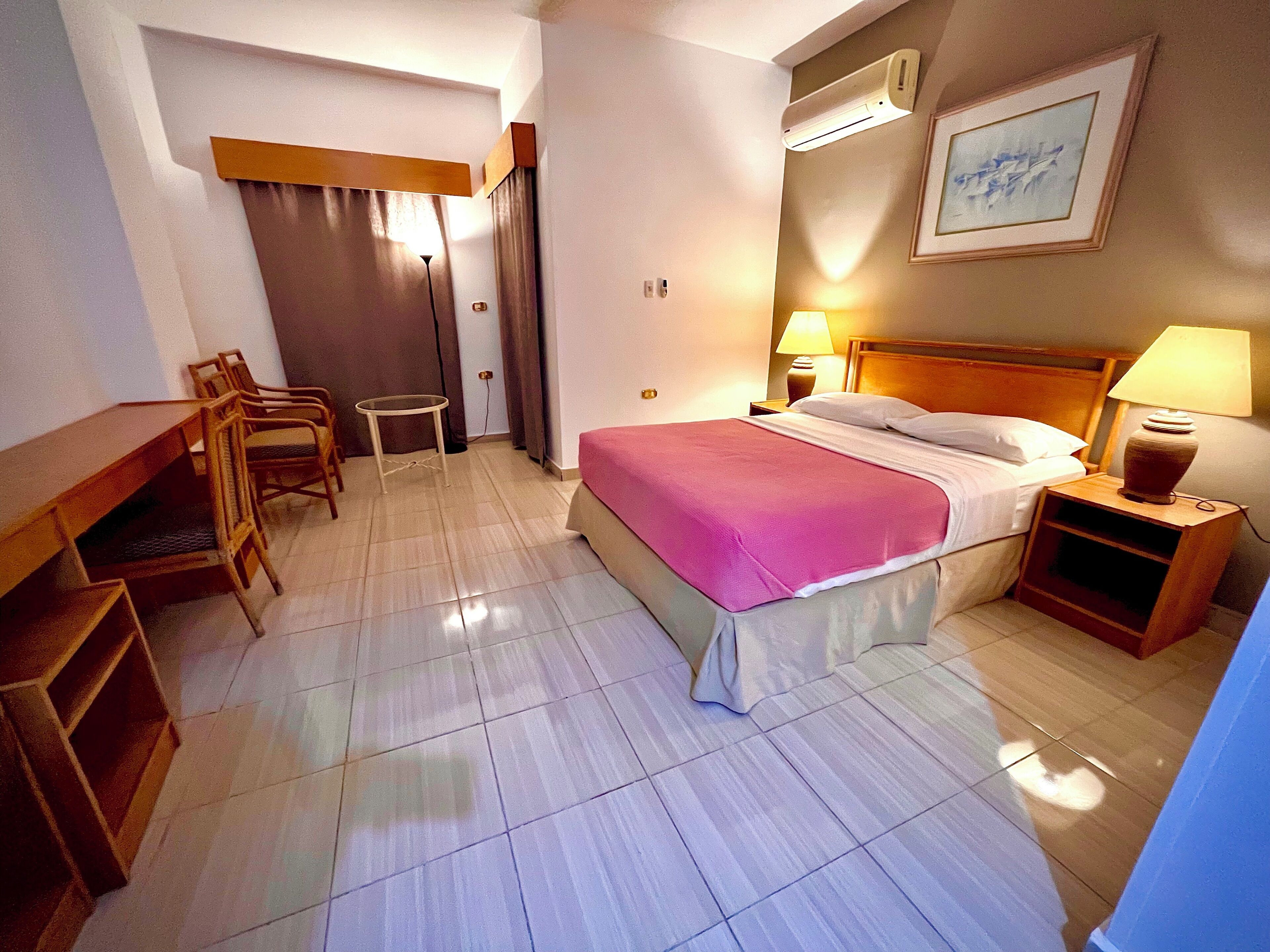 Une chambre d’hôtel comprenant un lit, des tables de chevet, un bureau et des chaises.