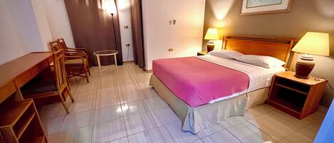 Une chambre d’hôtel comprenant un lit, des tables de chevet, un bureau et des chaises.