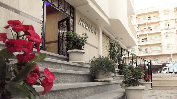 A hotel entrance with stone steps, potted plants, and a sign. - Masaya Suites (Hurghada)
