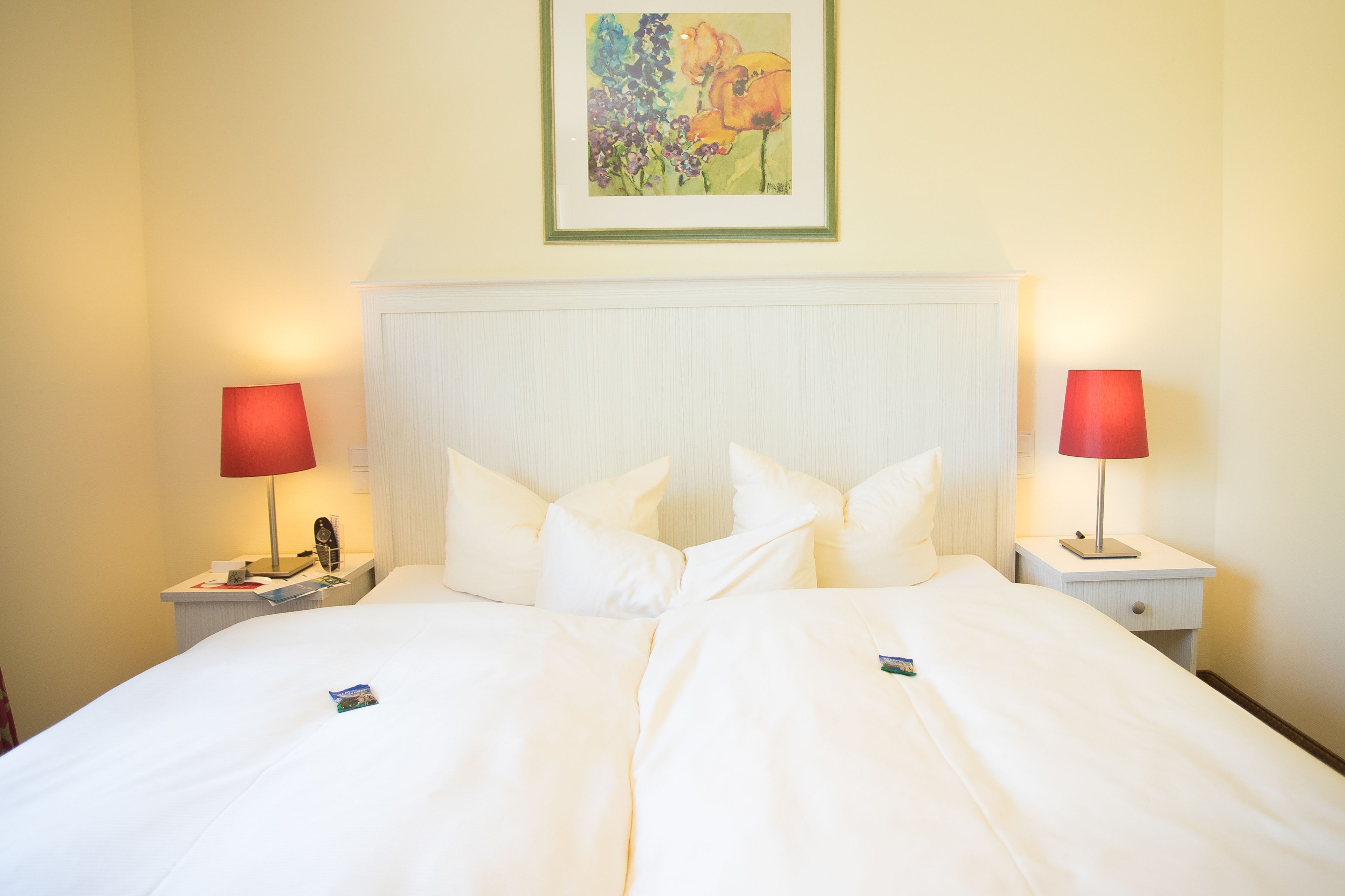 A hotel room with a large bed, two bedside tables, and a painting on the wall.