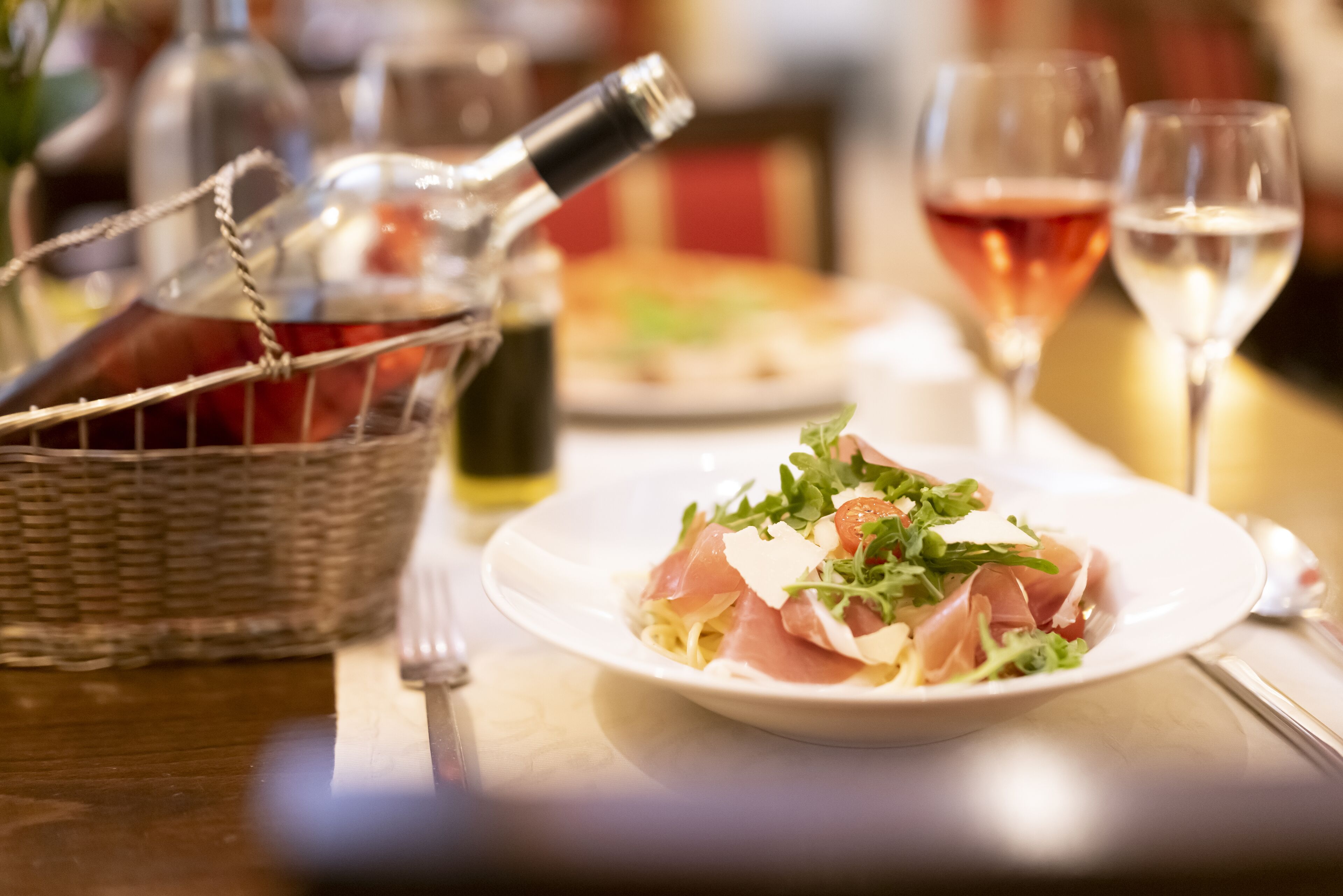 A dining table with a plate of food, a wine bottle, and glasses.