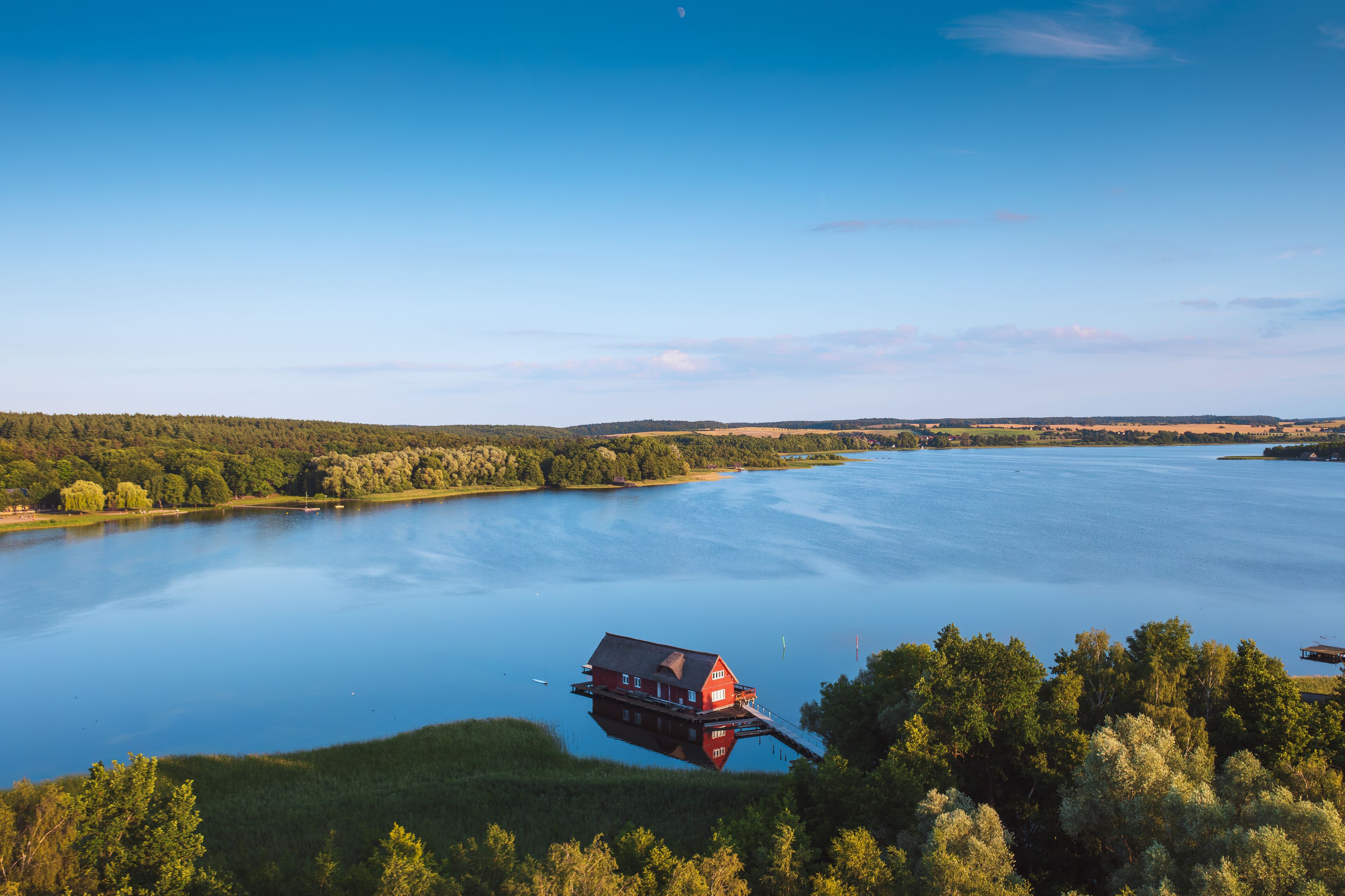Una casa flotante en un lago tranquilo rodeado de colinas boscosas.