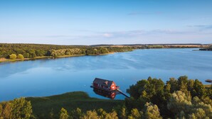 A houseboat on a calm lake surrounded by forested hills.
