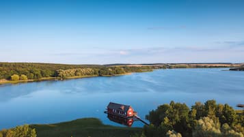Una casa flotante en un lago tranquilo rodeado de colinas boscosas.