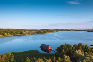 A houseboat on a calm lake surrounded by forested hills.