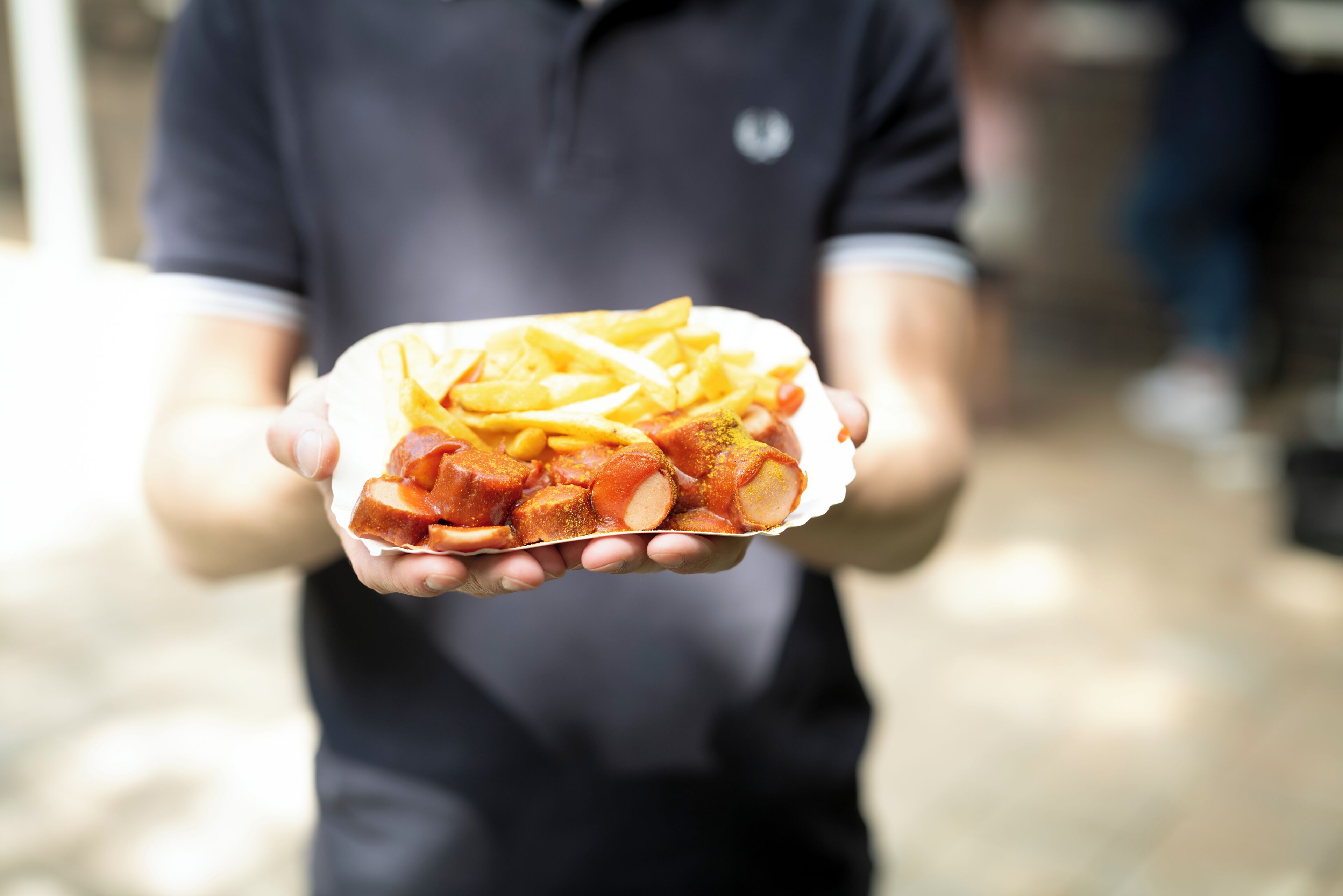 A person holding a paper container with food items.