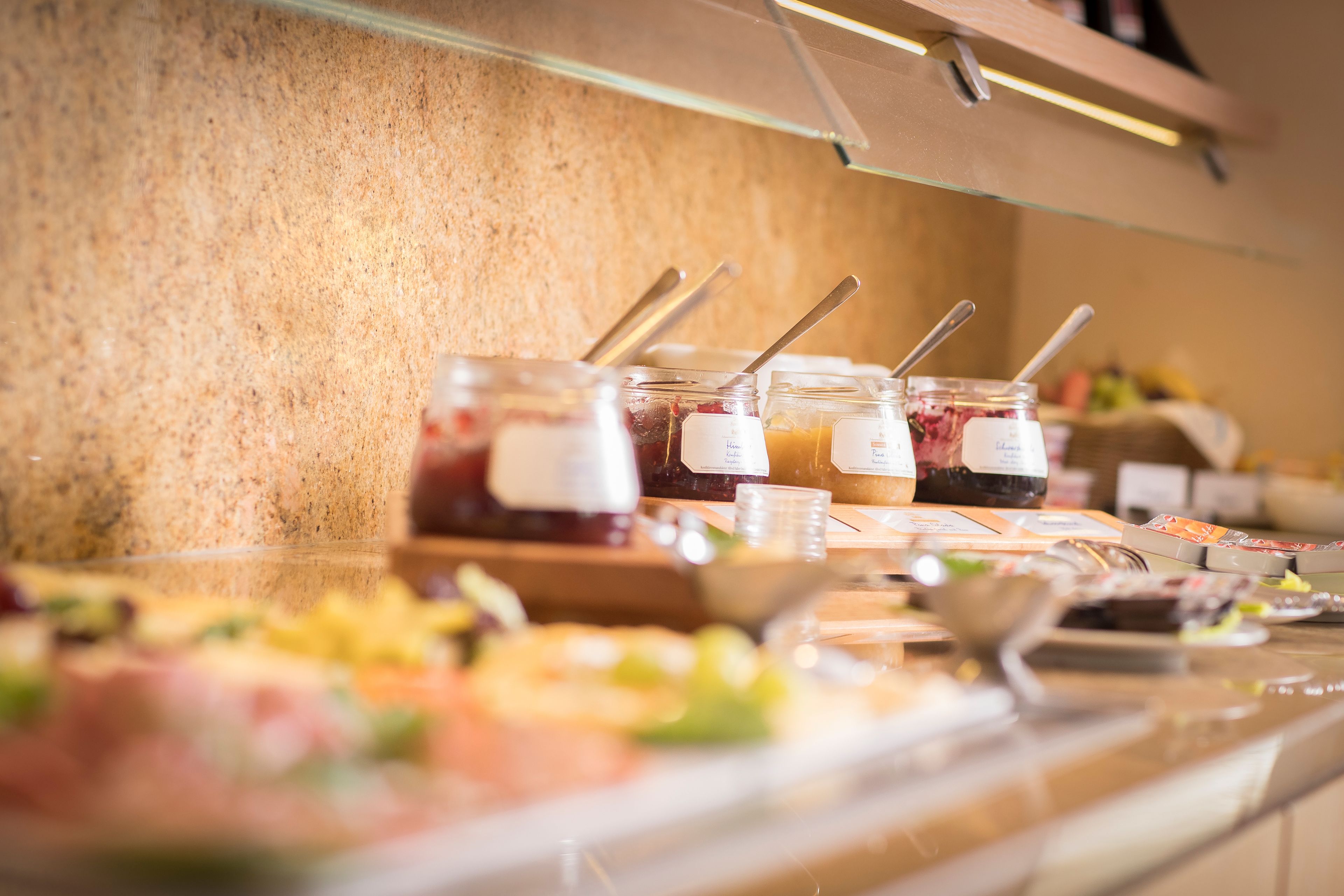 A buffet with various food items and condiments, including jars of sauces and a bowl of salad.