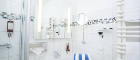 A modern bathroom with a glass shower enclosure, a white sink, a mirror, and a towel rack.
