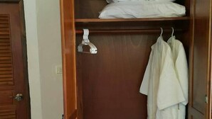 Une armoire en bois avec un espace pour suspendre les vêtements et une étagère pour les oreillers.