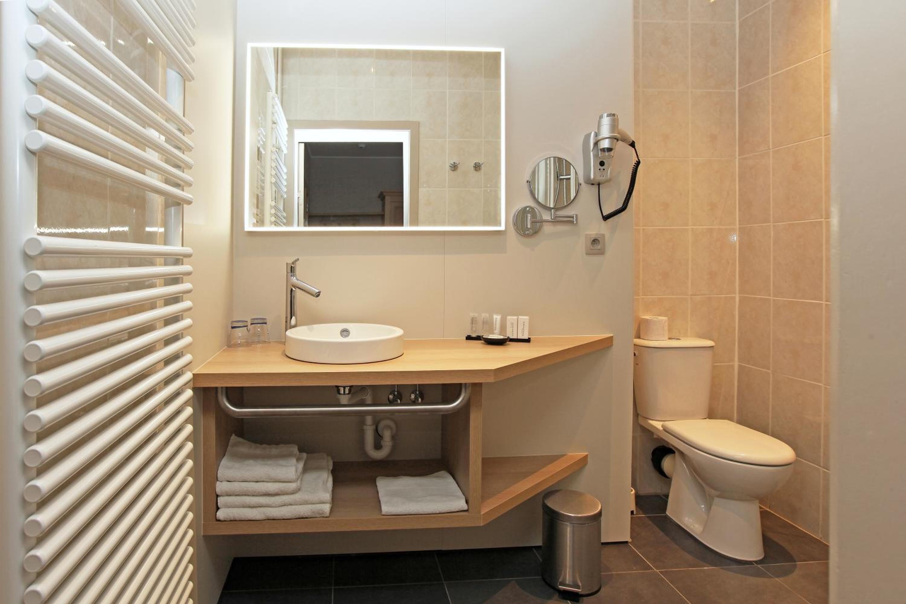 Egy modern fürőszoba beépített mosdótállal, tükörrel, törölközőtartóval és WC-vel.