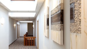 Un pasillo con obras de arte en las paredes, un banco de madera y un techo con tragaluces.