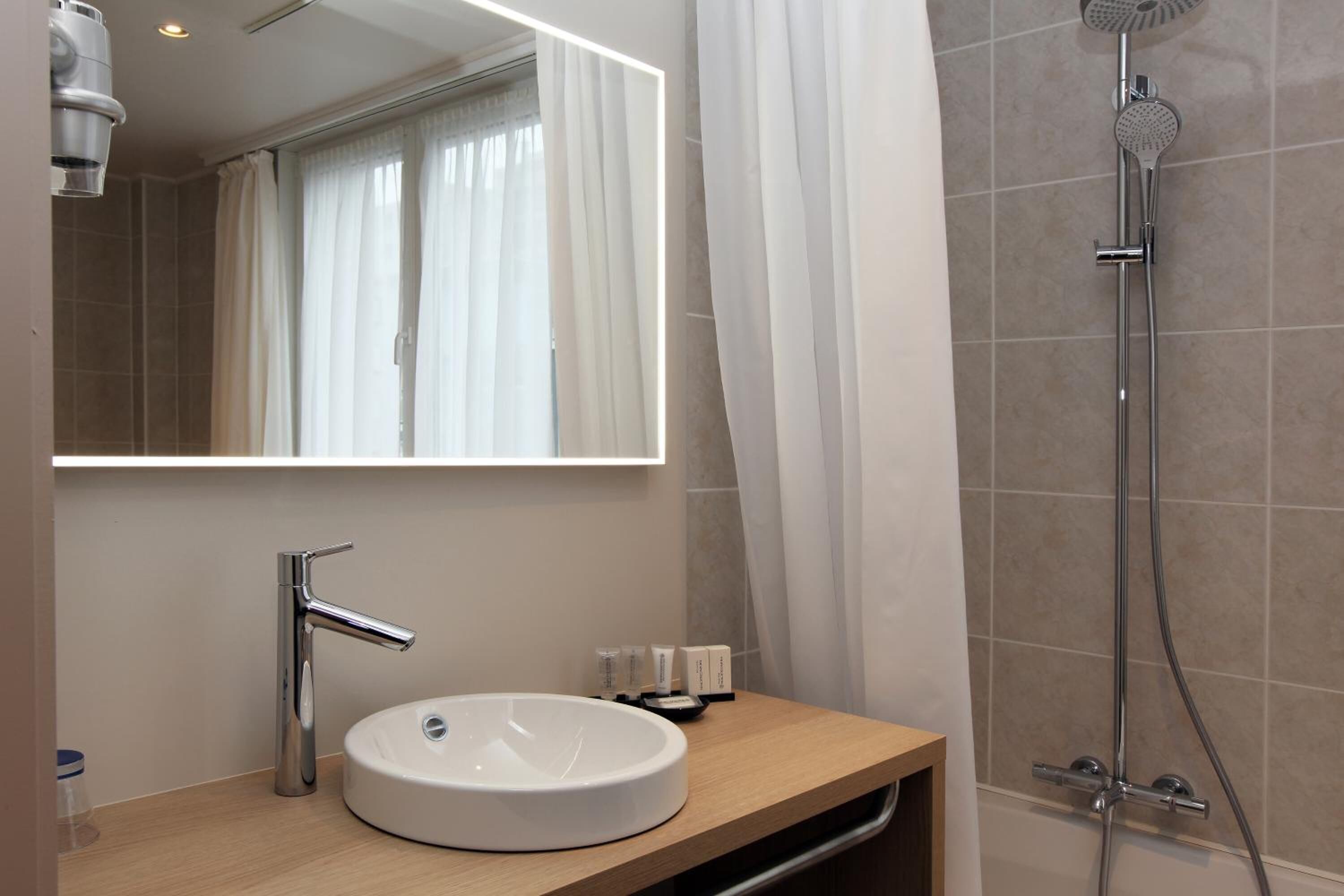 Une salle de bain moderne avec un lavabo rond, un miroir et une douche.