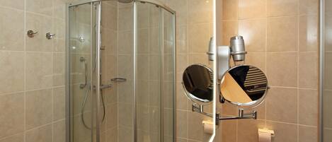 A modern bathroom with a glass-enclosed shower, a round mirror, and a towel rack.