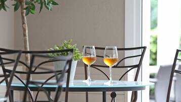 Une table en verre, deux verres à vin, une plante en pot et une chaise.