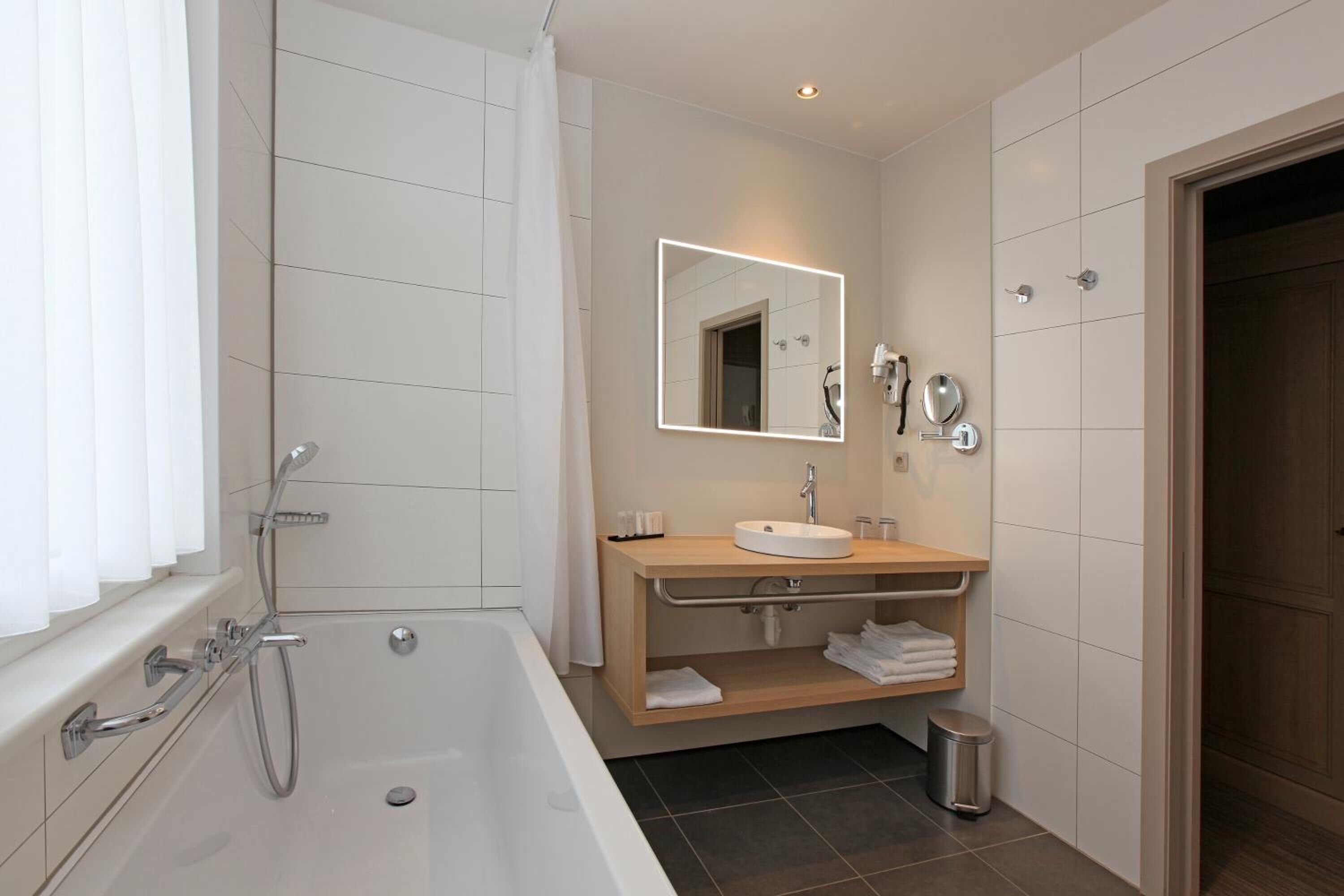 Een moderne badkamer met een bad, een wastafel met spiegel en een douche.
