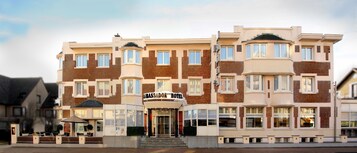 Un hotel de varios pisos con una entrada destacada, grandes ventanales y un estilo arquitectónico clásico.