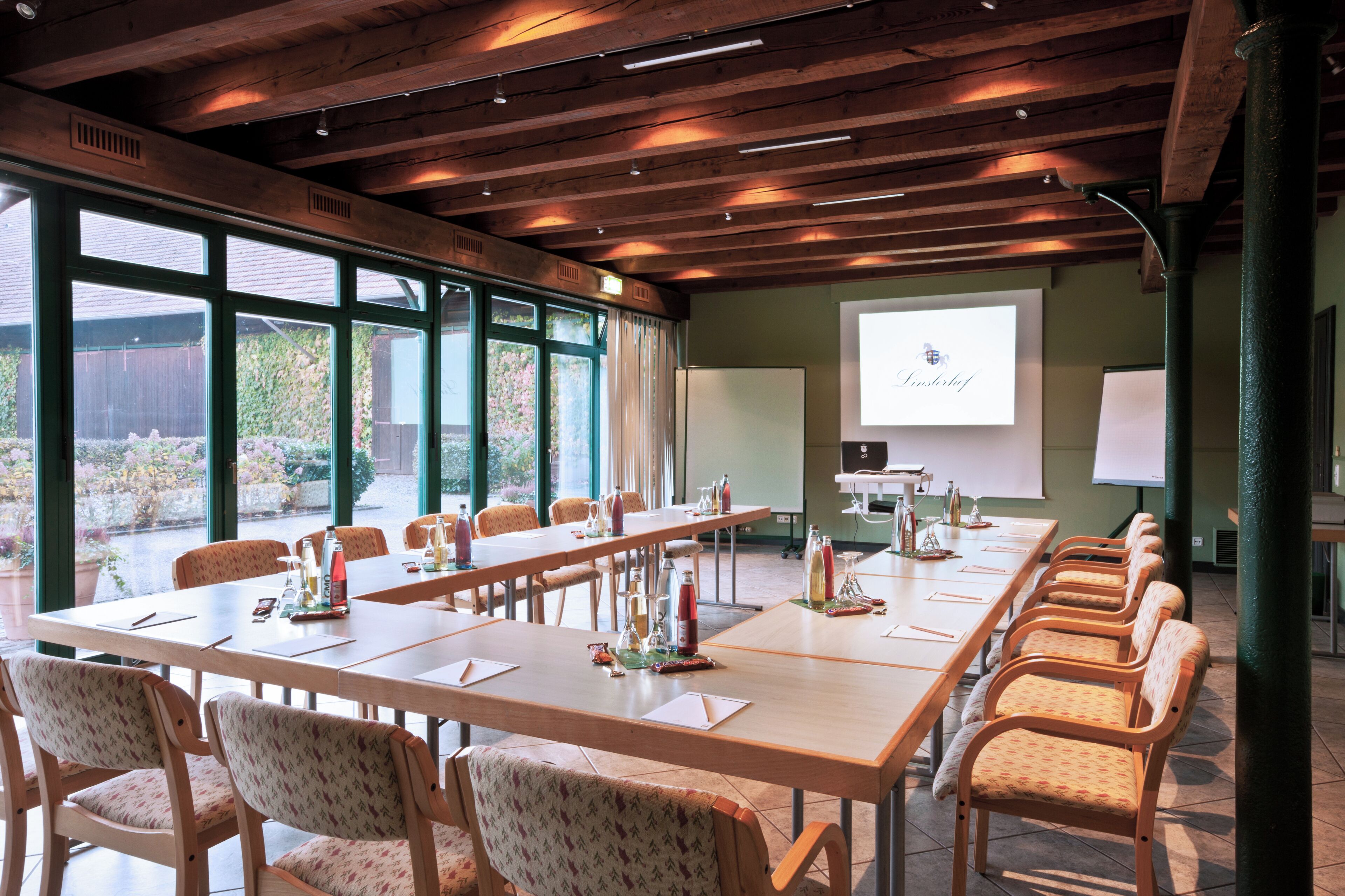 A conference room with a long table, chairs, a projector screen, and a presentation area.