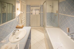 A bathroom with a sink, mirror, towel rack, and shower area.