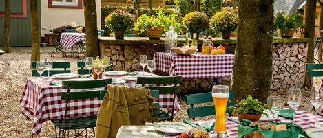 An outdoor dining area with checkered tablecloths, green chairs, and potted plants.