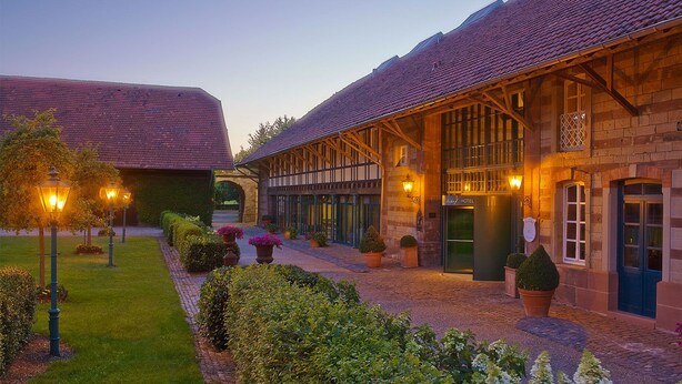 Een traditioneel Europees hotel met een binnentuin, stenen muren en een bord dat aangeeft dat het een hotel is.