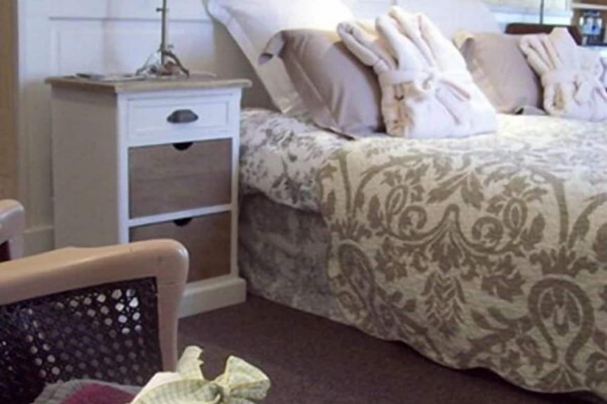 A cozy bedroom with a bed, two bedside tables, a chair, and a small table.