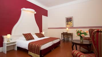 Habitación de hotel con una cama grande, un escritorio, una silla y un florero con flores.