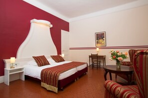 A hotel room with a large bed, a desk, a chair, and a vase of flowers. - Les Tourelles (Sainte-Maxime)