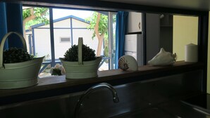 Eine Küchenarbeitsfläche mit zwei weißen Töpfen, einem Spülbecken und einem Fenster mit blauen Vorhängen.